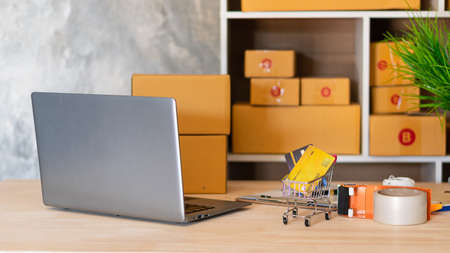 sme business idea with cart and credit card laptop on table with yellow back box
