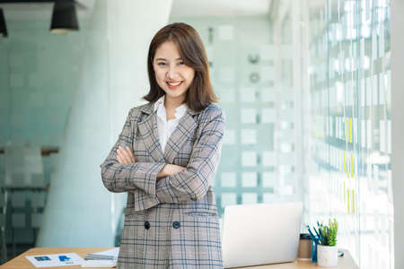 Asian businesswoman standing with her arms crossed looking at the camera at the office financial accounting conceptの写真素材