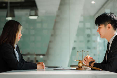 Male attorneys or judges consult team with female business clients. with hammers and scales next to...
