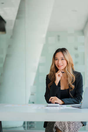 Asian business woman Working on laptop on desk . Independent woman reading financial graph chart. Marketing analysis planning hand of a girl working in the officeの写真素材