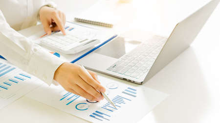 Close-up of businessman holding pen pointing to graph graph in document Corporate financial...