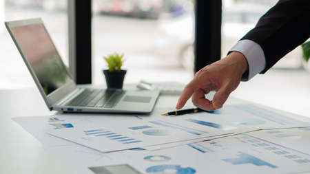 Close-up of businessman holding pen pointing to graph graph in document Corporate financial...
