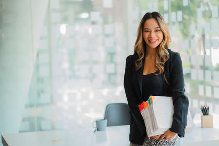 Asian businesswoman holding financial documents in front of her desk, accounting concept.