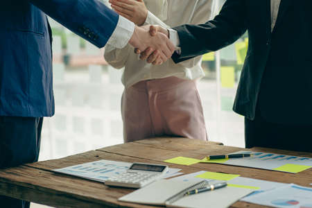 Two businesspeople shaking hands during a meeting, contacts, greetings business partners. With graph...