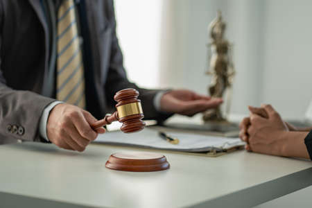 Businessman and lawyer man discussing legal matters and signing contract papers with judge's hammer...