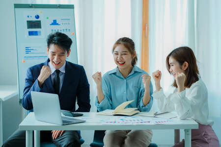 Asian and Caucasian corporate executives discuss business in a conference room of three young...