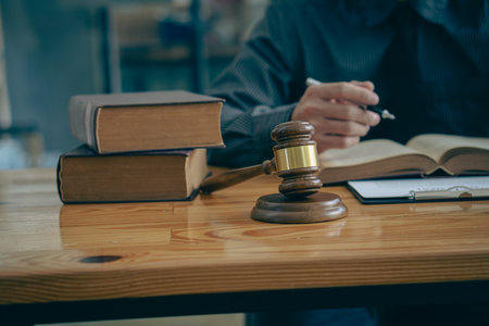 Business lawyers work hard at their desks with books and papers. The judge uses a hammer at the...