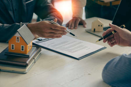 Home agents talk to new home buyers and offer good interest rates and calculate clients on mortgage financing to help make real estate concept decisions.の写真素材