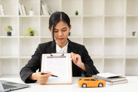 Young Asian car sales representative makes a successful car loan contract with a customer and signs a concept car insurance contract.の写真素材