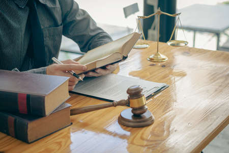 Concepts of justice and lawyers discuss contract paperwork with brass scales on a table with a...