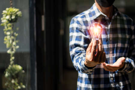 Man holding a light bulb, new ideas, technological innovations and creativity. with a sparkling light bulb Concept with innovation and inspirationの写真素材