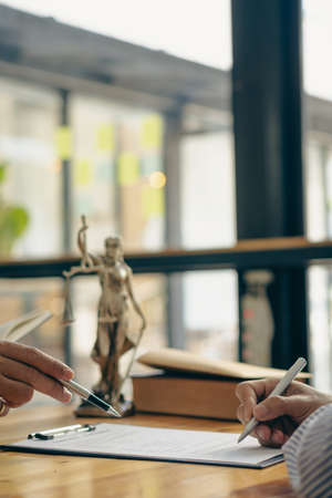 Business people or lawyers discussing contracts or business deals at a law firm. Justice advice service concept with hammer and goddess of justice beside, vertical image.の写真素材