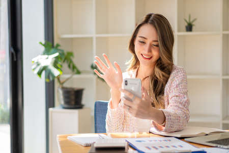 Happy woman working using multiple devices on her desk at home. Executives working online with laptops and desktop phones at the office.の写真素材