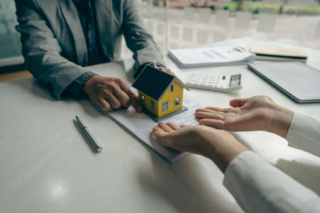 The real estate agent discusses the terms of the home purchase contract and asks the client to sign the documents to legally enter the contract. Ideas for selling a house at an offの写真素材