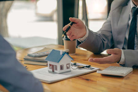 The real estate agent discusses the terms of the home purchase contract and asks the client to sign the documents to legally enter the contract. Ideas for selling a house at an offの写真素材