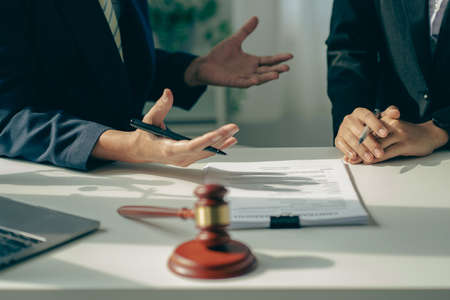 Male attorneys or judges consult teams with clients, business and legal services. The consultant presents the contract signed with the hammer placed in front and concept of justiceの写真素材