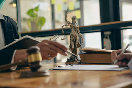 Male attorneys or judges consult teams with clients, business and legal services. The consultant presents the contract signed with the hammer placed in front and concept of justiceの写真素材