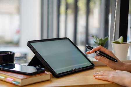 Close-up of businessman using blank screen digital tablet at desk while searching for business...