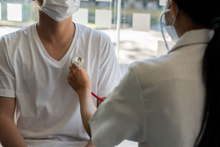 A doctor uses a stethoscope to examine the patient's heartbeat. The focus is on the stethoscope and...