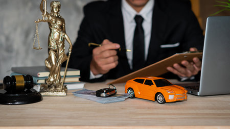 Small cars, keys and scales. Goddess of justice with hammer, money and laptop, and businessman holding a pen to sign a contract under car title approval concept.の写真素材