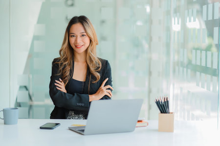 Freelance young Asian businesswoman working on laptop computer in modern office. make an account analysis report real estate investment information Accounting concepts, financial sの写真素材