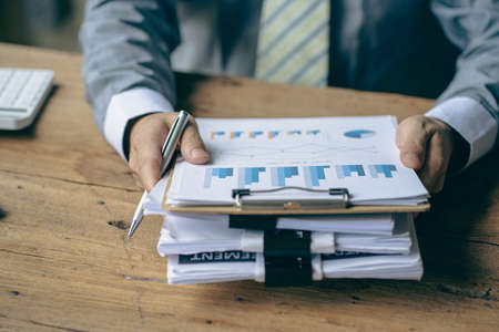 Accountants work with stacks of financial documents and analyze financial data to design modern office strategies and plan new business development ideas. Working on a new startupの写真素材