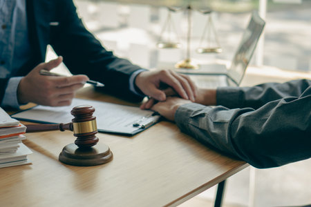 Male businessman and lawyer consulting with the client team on law, discussing and signing office contract with judge's scale and hammer on legal services concept table.の写真素材