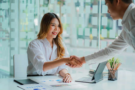 Two confident business people shaking hands during office meeting. Modern, greeting agreement concept.の写真素材