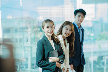 Young Asian business team working with laptops on financial documents with happy smiles. Group of business people meeting in a modern office Design and Concept Planningの写真素材