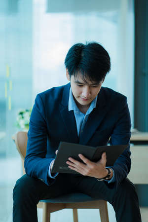 Handsome young Asian businessman sitting alone in the officeの写真素材