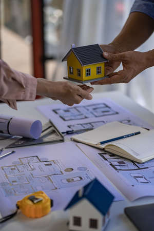 Engineer and architect team meeting with helmet and house on construction tool table With blueprints...
