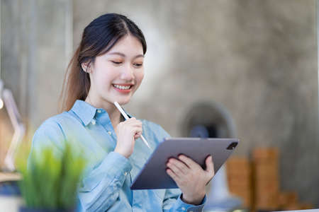 A young Asian female accountant or manager sits at her desk. Reading and reviewing account sales in...