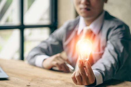 Businessman holding a light bulb, new idea, cutting-edge technology and creativity to save energy