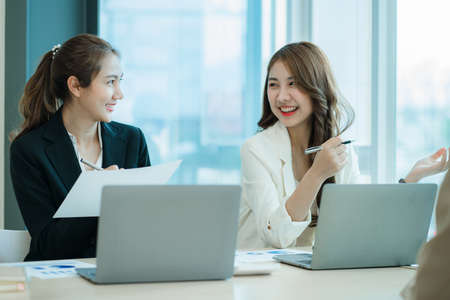 Two Asian female accountants working in the office with laptop computers and financial documents on the table.の写真素材