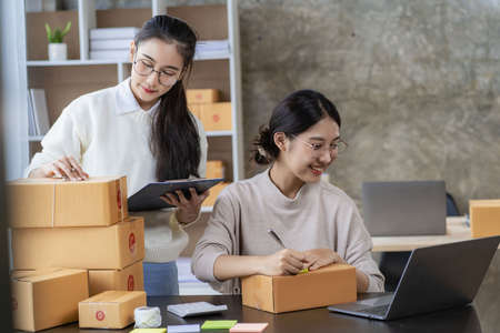 Two independent Asian women working from home small business owners inspect products before delivering them to customers online. shipping packaging Online marketing for SMEs, startの写真素材