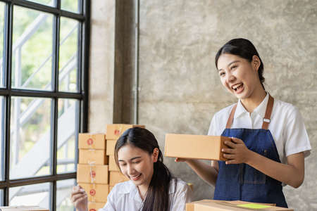 Two independent Asian women working from home small business owners inspect products before...