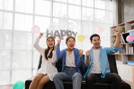 Friendship, Leisure and People Concept - Happy friends sitting on the sofa and watching football or soccer games on TV at home.の写真素材