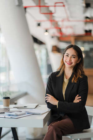 Asian businesswoman or accountant using laptop while analyzing financial data with weekly schedule in the modern officeの写真素材