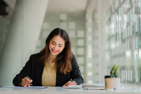 Asian businesswoman or accountant using laptop while analyzing financial data with weekly schedule in the modern officeの写真素材