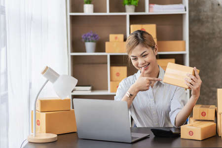 New business owner Asian woman working at home office Packaging on background SME entrepreneur...