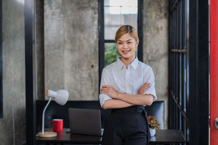 asian girl smiling sitting in front of a desk in the officeの写真素材