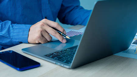 An accountant using a mobile smartphone while working analyzes business reports in the workplace....