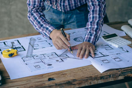 An engineer or architect working on a new project on a construction site. With blueprints and using...