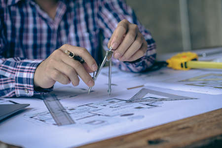 An engineer or architect working on a new project on a construction site. With blueprints and using...