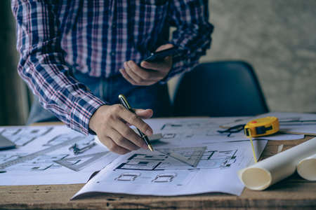 An engineer or architect working on a new project on a construction site. With blueprints and using...
