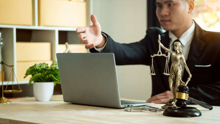 Asian male lawyer with legal services concept at online legal counseling office with hammer and laptop scales on table.の写真素材
