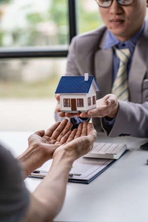 Male real estate agent hands customers keys and new home after signing leasing contract. About Mortgage and Home Insurance Offersの写真素材