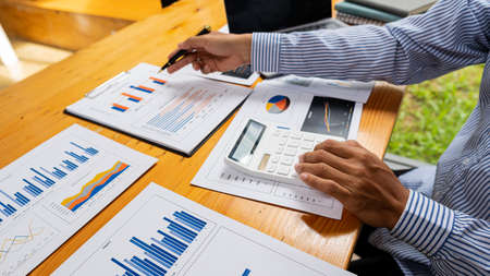 Female accountant using calculator and computer with pen in hand Man making money and calculating on...