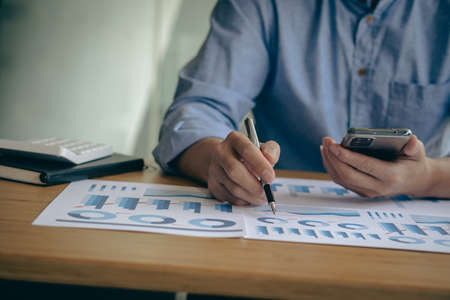 business man holding a smartphone and working on a laptop Trading graph data. Financial. Business...
