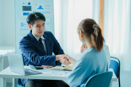 Smiling Caucasian businessman shaking hands greets female business partner with a successful meeting agreement. who are happy hand in hand, make a deal or get acquainted with an ofの写真素材